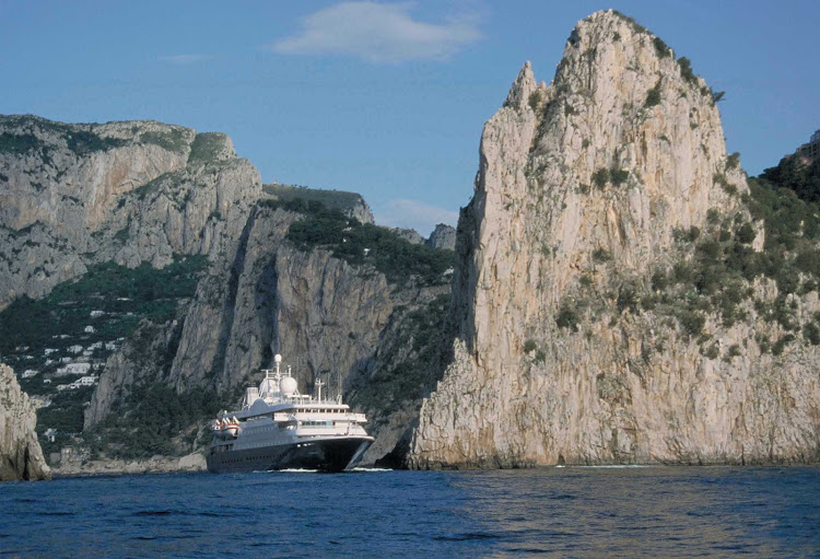 A SeaDream ship sails past a dramatic cliffscape in Capri, Italy. 