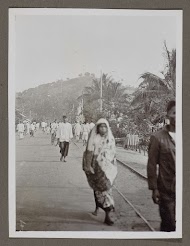 Mensen lopend op straat, langs een spoorlijn