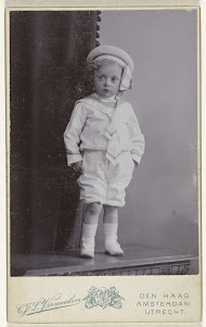 Studioportret van een kindje in een wit matrozenpak met  hoedje