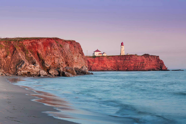 Red cliffs sit beneath the Havre-Aubert lighthouse on Iles De La Madeleine. The Magdalen Islands form a small archipelago smack in the middle of the Gulf of Saint Lawrence, Canada.