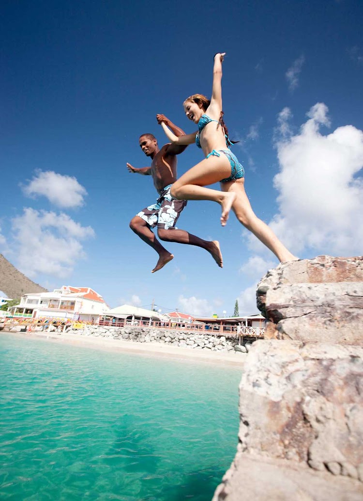 Visitors jumping from rocks to the sea in St. Maarten.