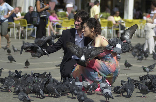 JFvenice-weddingcouple - Wedding couple overwhelmed by fowl in St. Mark's Square.