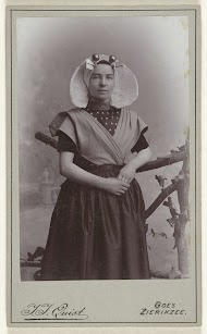 Studioportret van een vrouw in protestantse Zuid-Bevelandse klederdracht bij een hek