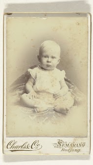 Studioportret van een zittende baby op een kleed