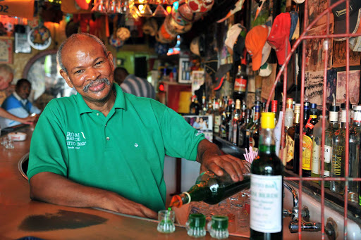 Curacao-Netto-Bar - Jesus M.E "Chu" Zimmerman, proprietor of the Notto Bar in Willemstad, Curacao, pours shots of the famous Ròm Bèrdè, a house-made green rum. 