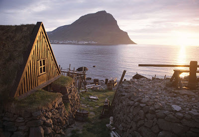 A traditional turf house by the sea at sunset in Iceland.