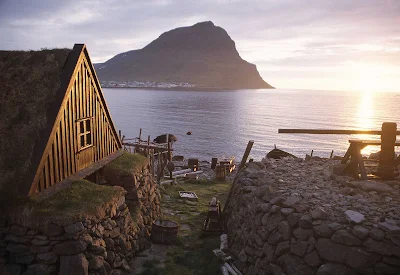 A traditional turf house by the sea at sunset in Iceland.