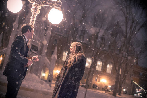 A light winter snow falls on people chatting in Quebec City.