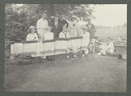 Groepsportret van de familie Kessler aan een buitentafel