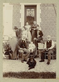 Mannen, vrouwen, een baby en een hond poserend voor een deur