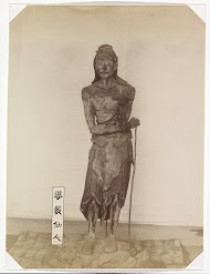 Sculptuur van de Onsterfelijke Basusen in de tempel Sanjusangendo in Kyoto: een staande figuur van een magere man met lang haar, een staf en een boekrol in zijn linkerhand, met naast hem op de grond een bord met de tekst  婆藪仙人, ’Basu sennin’ (‘de Onsterfelijke Basu’). Basu (sanskr. Vasu) wordt afgebeeld als een Indiase asceet; hij komt in Japanse boeddhistische tempels voor als een van de assistenten van Senju Kannon, de Duizendarmige Bodhisattva Avalokiteshvara.