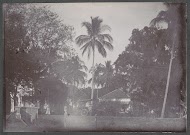 Voorbijgangers en een ossenkar op een weg, vermoedelijk op het terrein van een ziekenhuis in Nederlands-Indië