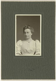 Studioportret van een vrouw in een witte jurk met opgespeld een broche