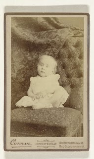 Studioportret van een baby in witte jurk op een stoel