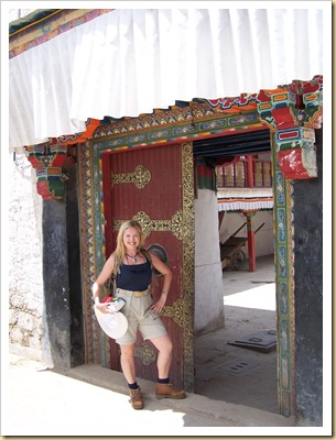 Tíbet, Lhasa, servidora posando ante el portal de un patio de vecinos.