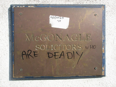 Plaque on wall for McGonagle solicitors with a sticker above it reading Thanks To, then the engraved McGonagle Solicitors, and underneath it has in black marker the words who are deadly - total text - thanks to McGonagle Solicitors who are deadly