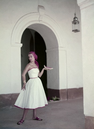 Model is wearing a strapless white cotton dress with a matching headkerchief, by Pat Premo and sandals by Bernardo 1953