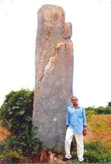 Freelance archeologist K. Venkateswara Rao stands beside the menhir which he discovered at Karampudi mandal in Guntur district [Photo: T. Vijaya Kumar]