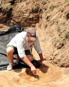 Tim Pauketat, a professor of archeology at the University of Illinois, Champagne Urbana, carefully uncovers what he hopes to be a piece of Mississippian pottery at a dig site in Trempealeau Wis. 
