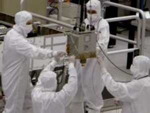 Members of NASA's Mars Science Laboratory team carefully steer the hoisted Chemistry and Mineralogy (CheMin) instrument during its June 15, 2010, installation into the mission's Mars rover, Curiosity. 