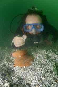 Chas Francoviglia, a member of the “Gold Hound” crew, holds up a gold coin found June 19 off Indian River Shores. Below him is a pot shard from a ship in the 1715 fleet.