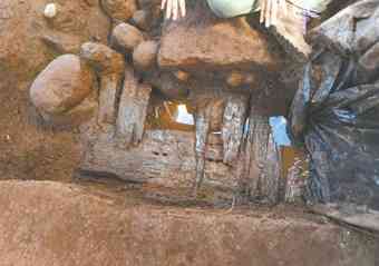 Water seeps from the ground where a section of wooden pier has been uncovered.