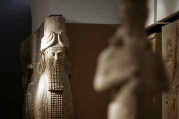 A statue is lit by natural light inside the Assyrian Hall of the Iraqi National Museum
