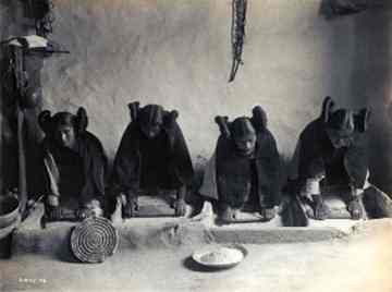Photo of four young Hopi women milling grain by Edward Curtis. 