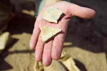 Hackbarth holds up pottery shards.