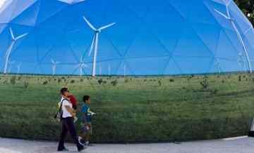 A family passes by one of the stands promoting green energy at the Climate Village in Cancun, Mexico.