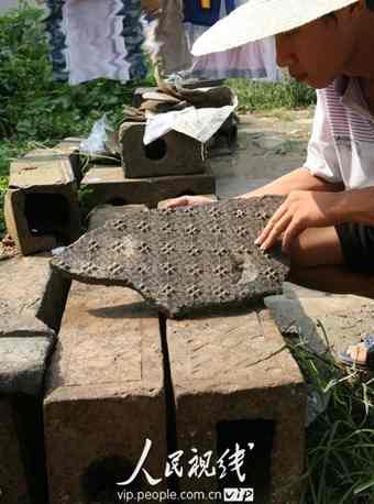 An archaeologist imitating and labeling a piece of ancient brick with delicate decorative designs in Baofeng County, Henan Province.