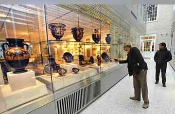 Visitors examine the exterior-facing display cases that rim the new exhibit space for The Johns Hopkins Archaeological Museum. At left are Athenian Black-Figure Amphora, on loan from the Baltimore Museum of Art. (Amy Davis, Baltimore Sun / December 4, 2010)