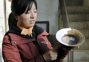 新华社照片，郑州，2010年1月12日<br />    河南新郑望京楼遗址新发现夏商两座大型城址<br />    1月12日，望京楼遗址发掘队队长吴倩展示出土文物“原始瓷尊”。<br />    郑州市文物考古研究院日前在对河南省新郑市望京楼遗址考古发掘中，发现了夏代和商代两座大型城址，并发现了外廓城，城址总面积达168万平方米。专家初步推测，夏代城址可能为夏之某一方国都邑，商代城址则可能是商代前期的一座军事重镇。<br />    新华社发（双瑞摄）