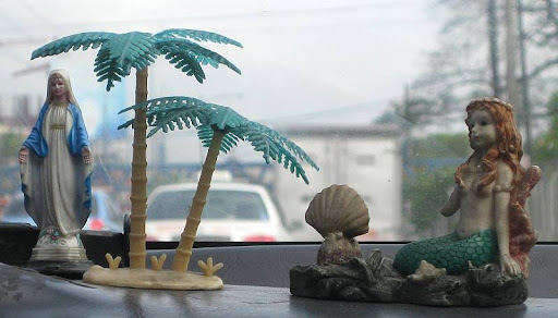 the Virgin Mary and a mermaid on a taxi's dashboard