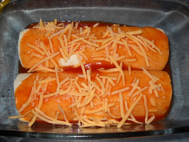 enchiladas in pan with sauce and cheese on top ready to bake