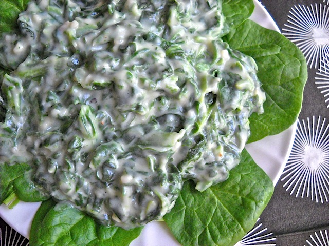 Creamed Spinach on leafy greens placed on white plate 