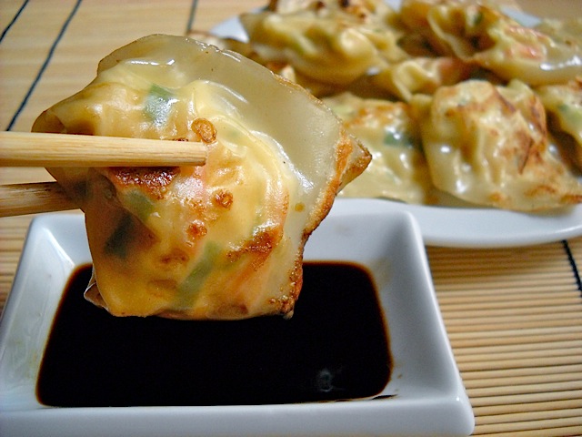 Lobster Wontons being held with chopsticks and dipped in soy sauce 