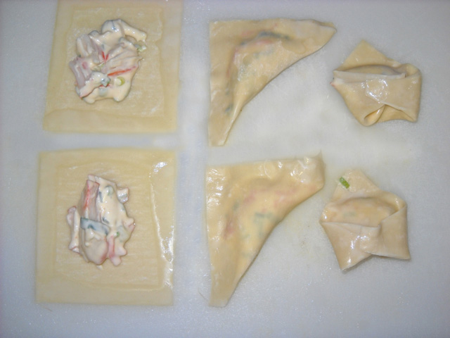 wontons on counter with spoonful of filling in them and folded over 