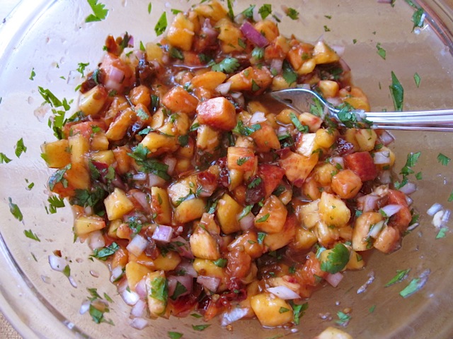 chipotle peach salsa in clear mixing bowl with spoon 
