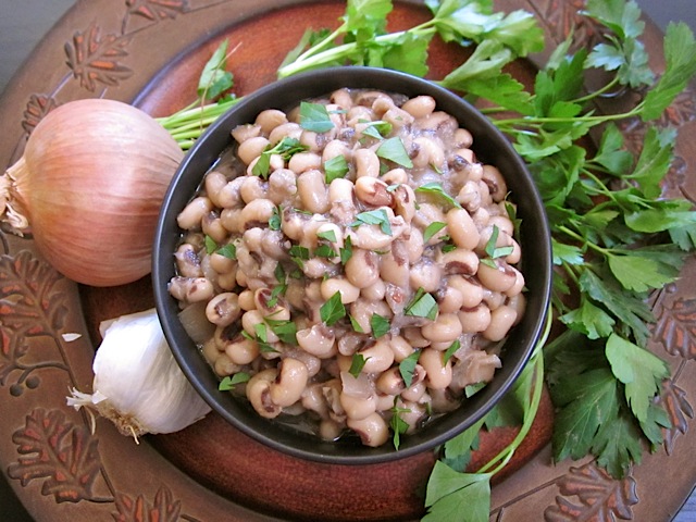 black-eyed peas in black bowl with onion, garlic and cilantro staged on the side 
