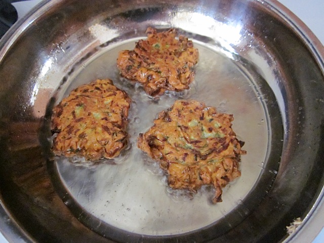 three browned zucchini fritters in pan 