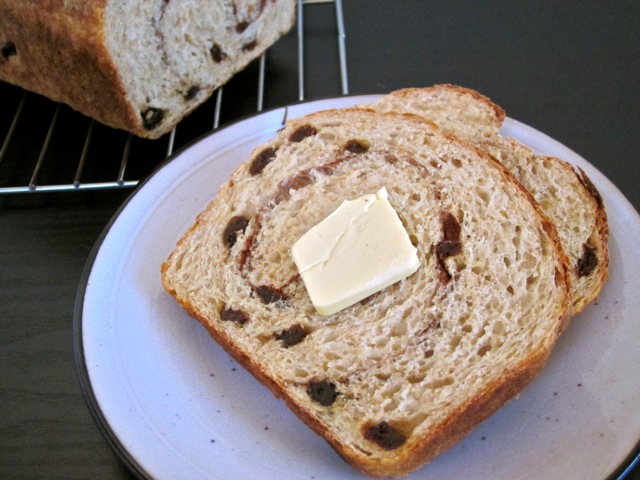 two slices of cinnamon raisin no knead bread on white plate with butter