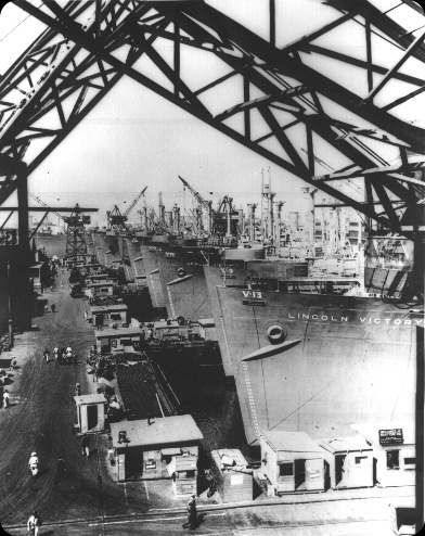 Victory cargo ships are lined up at a US west coast shipyard for final outfitting 1944
