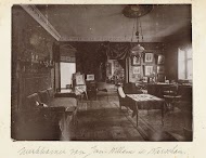 Gemeubileerde kamer met portretten aan de wand