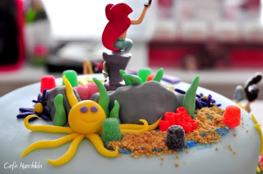 At the back of the cake, behind the rocks is a yellow, purple-eyed octopus.
