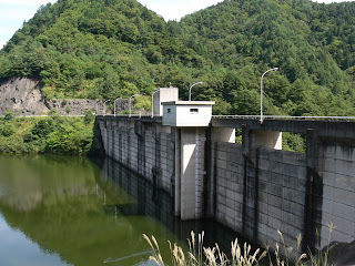 Vista dell'argine sul lato lago della diga dal sito della diga in riva destra