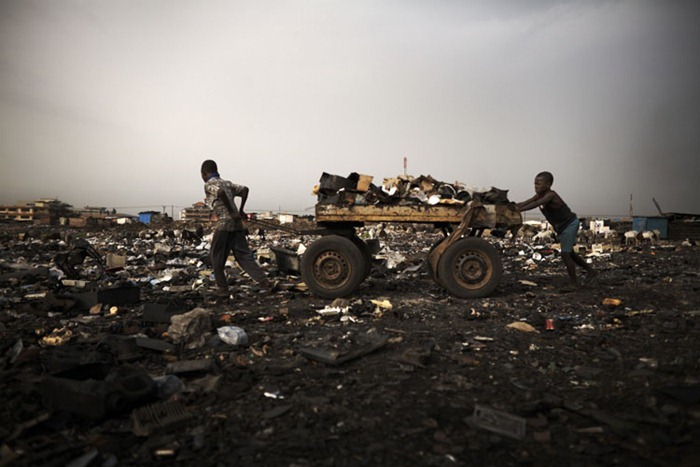 Children push a cart loaded with scrap, including computers keyboards and other e-waste, at Agbogbloshie dump, Accra, Ghana.