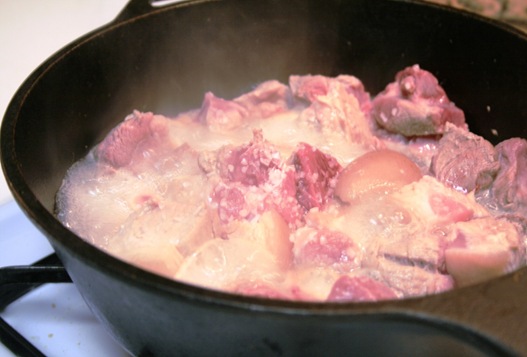 cooking pork carnitas in a cast iron pot