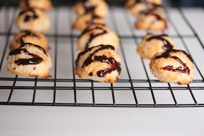 coconut macaroons drizzled with chocolate on a baking sheet