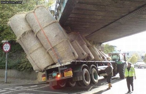 photo of a truck loaded too high and stuck under a bridge